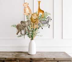 a vase filled with animals and plants on top of a wooden table next to a white wall