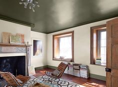 a living room filled with furniture and a fire place under a chandelier in front of two windows