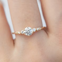 a woman's hand with a three stone diamond ring on her left hand,