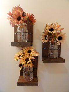 two mason jars filled with sunflowers are on the wall next to each other