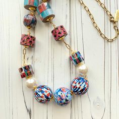 "The art of decoupage is the creative technique used on this artsy long statement necklace with linked large beads. Vintage fabrics and textile prints are copied onto paper and scaled to size. The prints are cut into strips, given a brush of decoupage adhesive, and carefully applied to the wooden bead. This technique is repeated until the bead is completely covered. A final satin topcoat is applied to offer both a protective coat as well as a glossy finished look.  39\"L with lobster closure. Ma Artistic Beaded Necklace With Large Beads, Elegant Multi-strand Necklaces With Wooden Beads, Traditional Multi-strand Wooden Bead Necklaces, Vintage Multi-strand Beaded Necklace With Polished Beads, Vintage Multi-strand Wooden Beads Jewelry, Vintage Multi-strand Necklaces With Polished Beads, Long Statement Necklace, Beaded Statement Necklace, Bead Charm Bracelet