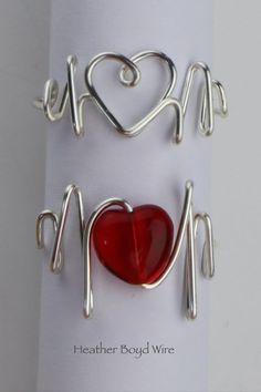 two pieces of metal with red glass in the shape of heart and handwritten words