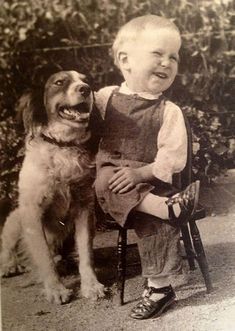 an old black and white photo of a young boy sitting next to a brown dog