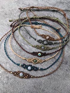 a bunch of bracelets sitting on top of a gray surface with beads and chains