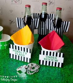 there are two soda bottles and three paper baskets on the table with other party items