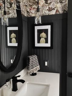 a white sink sitting under two mirrors in a bathroom next to a wall with pictures on it