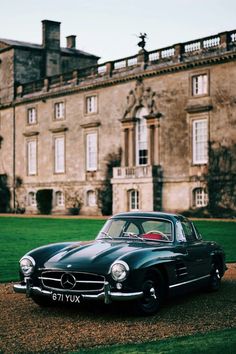 an old black car parked in front of a large building