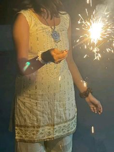 a woman holding a lit sparkler in her hand