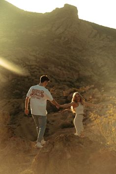 two people holding hands on top of a mountain