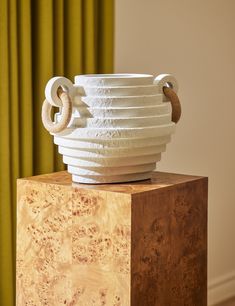 a white vase sitting on top of a wooden block