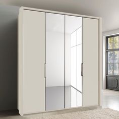 a white closet with mirrored doors in an empty room next to a rug and window