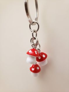 a red and white mushroom keychain hanging from a metal hook