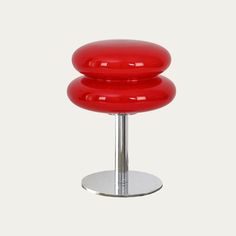 a red stool sitting on top of a metal base