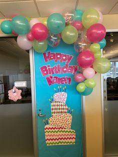 a birthday cake decorated with balloons and streamers in front of a door that says happy birthday karan