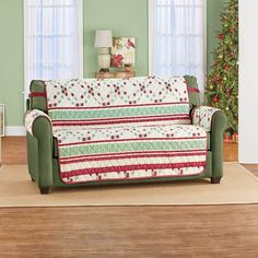 a living room with a christmas tree in the corner and a couch covered in a quilt