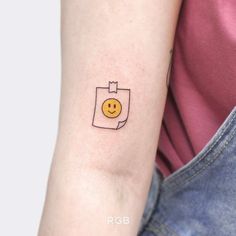 a woman's arm with a smiley face tattoo on the left side of her arm