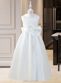 a white flower girl dress on display in a room