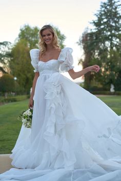 a woman in a white wedding dress posing for the camera with her hand on her hip