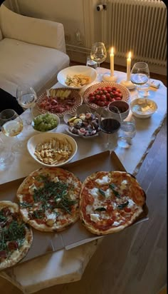 pizzas and other food on a table with candles