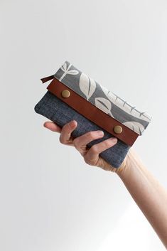 a hand holding a wallet with an animal print pattern