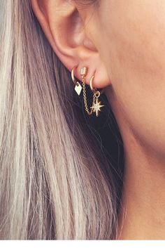 a close up of a person wearing ear clips with stars and moon charms on them