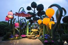 a garden with flowers and lights in the shape of trees, bushes, and mushrooms