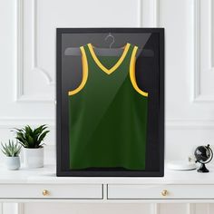 a green and yellow tank top hanging on a wall next to a white dresser with a potted plant