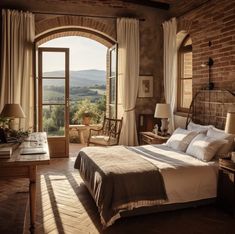 a bedroom with an arched window overlooking the countryside