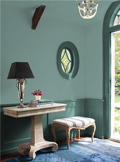 a room with green walls and blue rugs on the floor next to a table