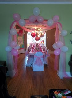 a table with pink and white balloons on it in the middle of a hall way