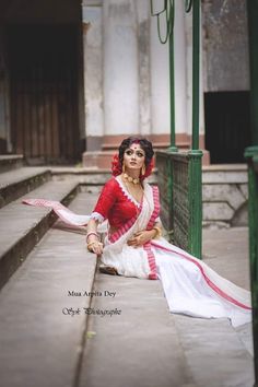 a woman sitting on the ground in a red and white sari