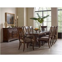 a dining room table with chairs and a potted plant in the middle of it