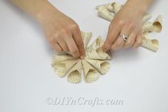 two hands are holding origami flowers made out of book pages