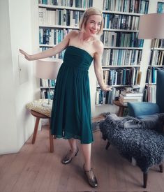 a woman standing in front of a bookshelf with her arms out to the side