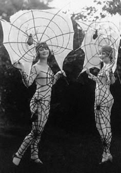 two women in bodysuits are holding parasols