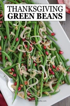 green beans with onions and pomegranates on a white serving platter