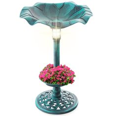 a lamp that is sitting on top of a stand with flowers in the pot underneath it