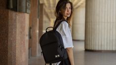 a woman with a black backpack is walking down the street