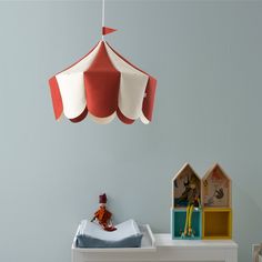 a baby crib with a stuffed animal in it and a toy house hanging from the ceiling