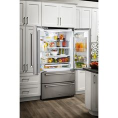 an open refrigerator in a kitchen with white cabinets