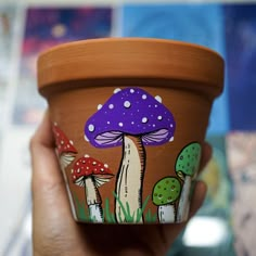 a hand holding a cup with mushrooms painted on it