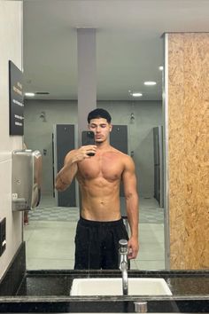 a shirtless man taking a selfie in front of a mirror with his cell phone