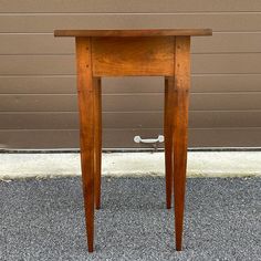 a small wooden table sitting in front of a garage door with a handle on it