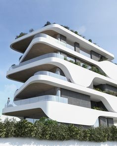 a tall white building with balconies and plants on top