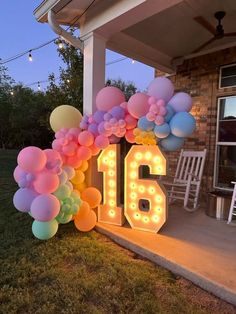 the number sixteen is lit up with balloons