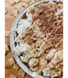 a bowl filled with food sitting on top of a wooden table next to crackers