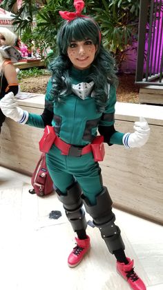 a woman dressed in green and red is posing for the camera