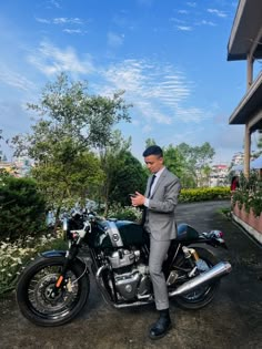 a man in a suit is standing next to a motorcycle and looking at his cell phone