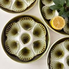 four green plates with leaves and lemon slices on the rims next to each other