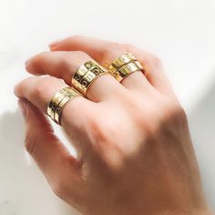 a woman's hand holding two gold rings